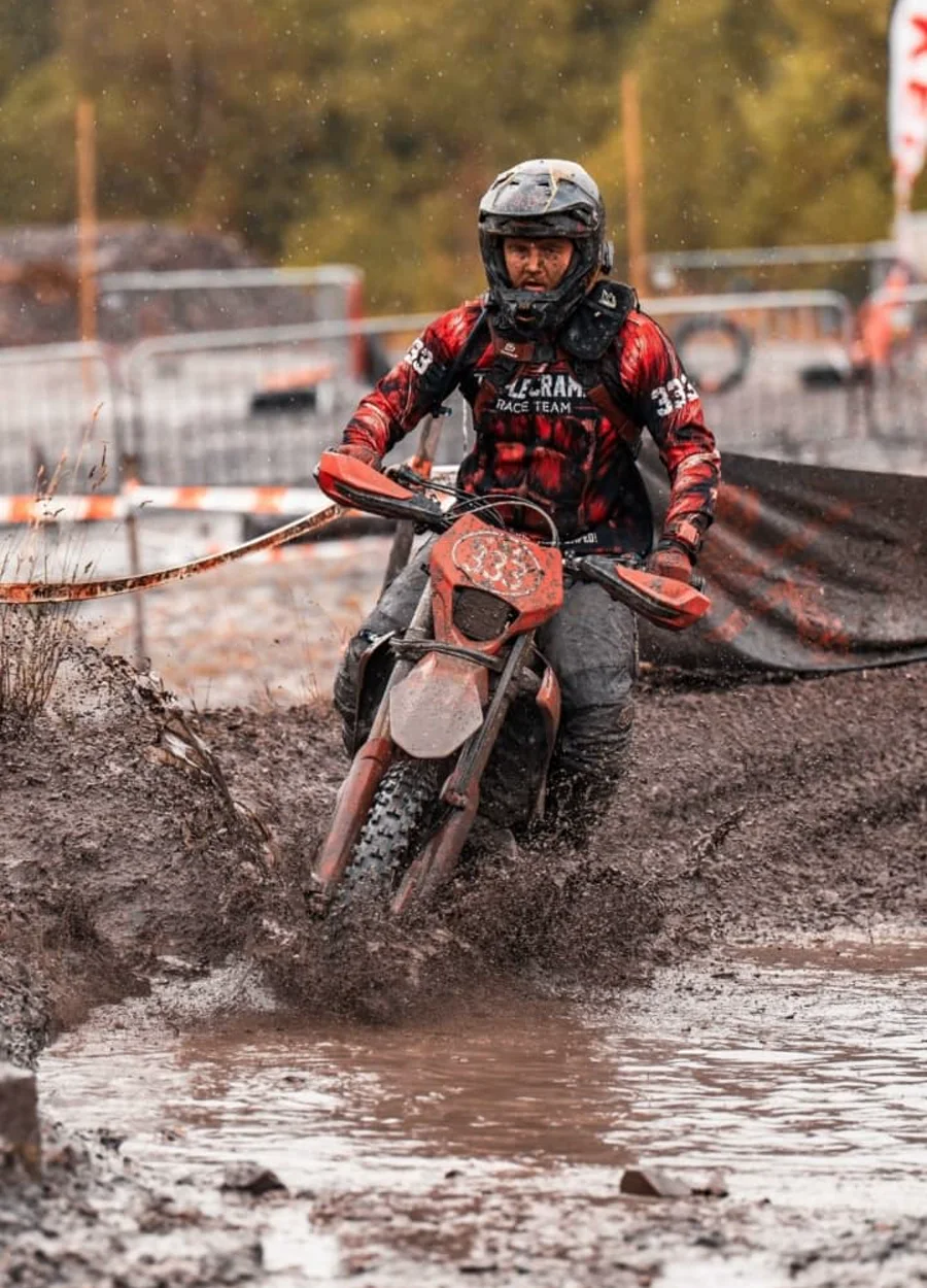 A rider driving through deep mud on an enduro course